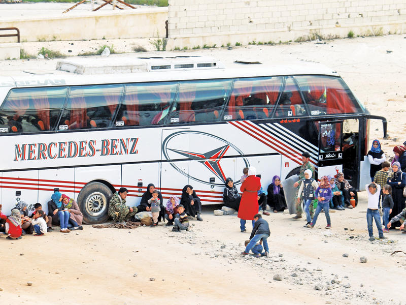 سوريات ينتظرن مع ذويهن إجلاءهن من حي الراشدين أمس (رويترز)