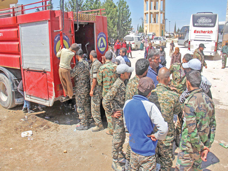 مقاتلون موالون للنظام أمام نقطة توزيع غذاء بحي الراشدين بحلب أمس (أ ف ب)