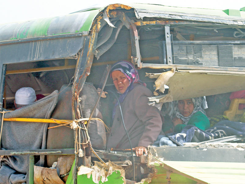 سورية مع ذويها على متن حافلة متهالكة تغادر منطقة الراشدين باتجاه حلب أمس (رويترز)