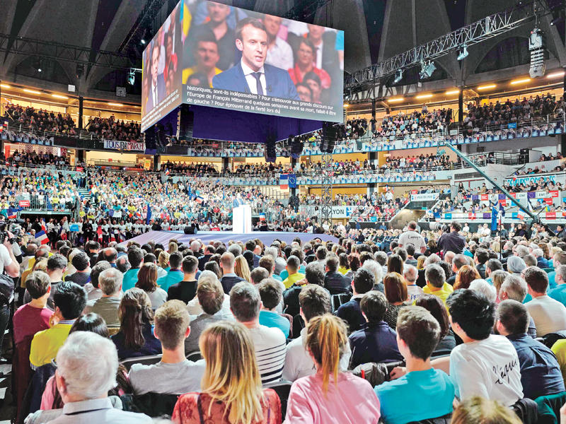  أنصار ماكرون يستمعون لخطابه في اجتماع عام بقصر الرياضة في ليون في 4 فبراير   (أ ف ب)