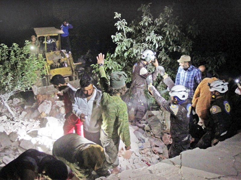 أعضاء الدفاع المدني يبحثون في جنح الظلام عن ناجين تحت أنقاض مبنى دمرته غارة جوية غرب مدينة إدلب فجر أمس (رويترز)