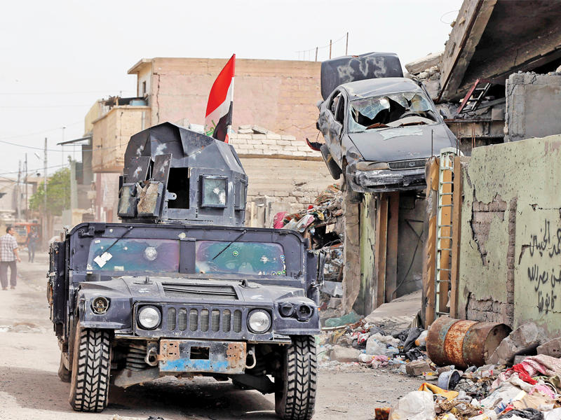 مدرعة أمام منزل قصفه «داعش» في أيمن الموصل أمس (رويترز)