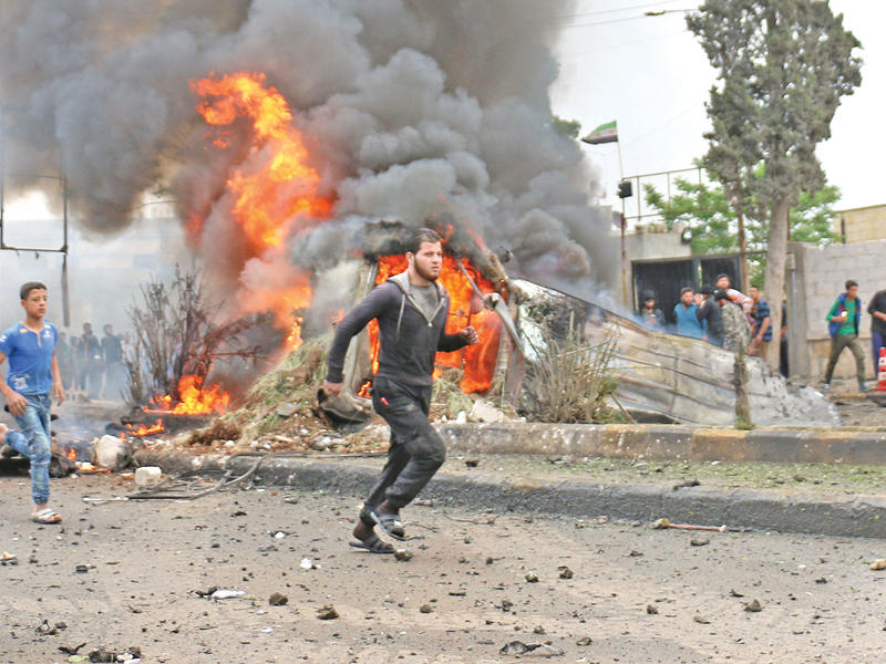 سوريون في منطقة الانفجار قرب مقر الحكومة المؤقتة بأعزاز اليوم (أ ف ب)