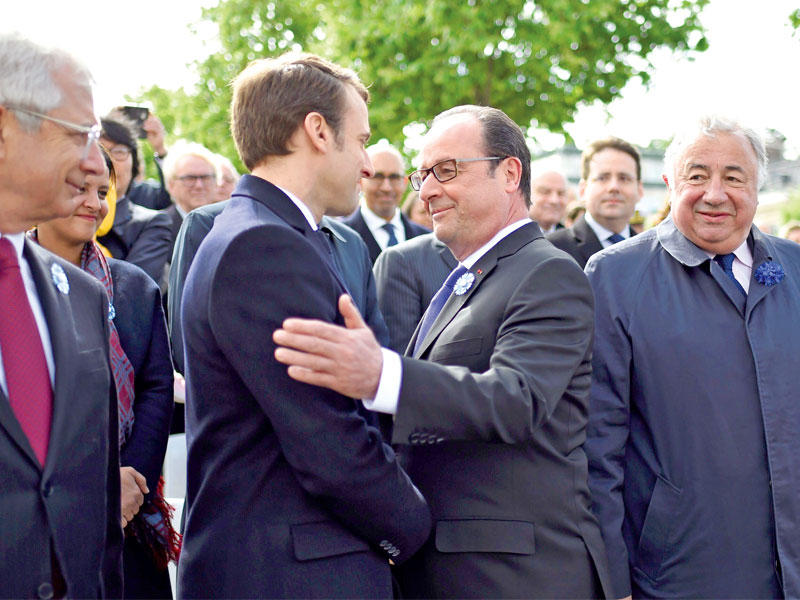 الرئيس هولاند إلى جانب ماكرون ويبدو الرئيس السابق نيكولا ساركوزي خلال احتفال بذكرى الانتصار على النازية في باريس أمس t(أ ف ب)