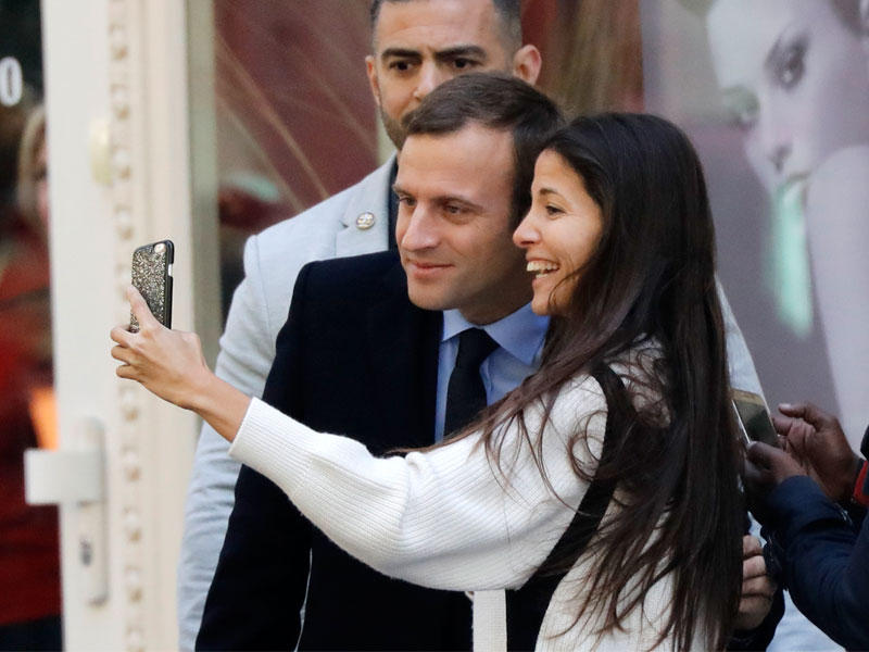 شابة تلتقط سيلفي مع ماكرون لدى خروجه من صالون الحلاقة اليوم في باريس (أ ف ب)