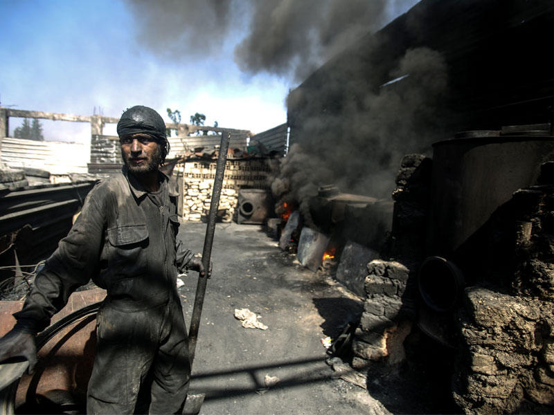 عامل في مصنع محلي لانتاج الوقود السائل والغازي من مخلفات البلاستيك في مدينة دوما المحاصرة قرب دمشق (إي بي أيه)