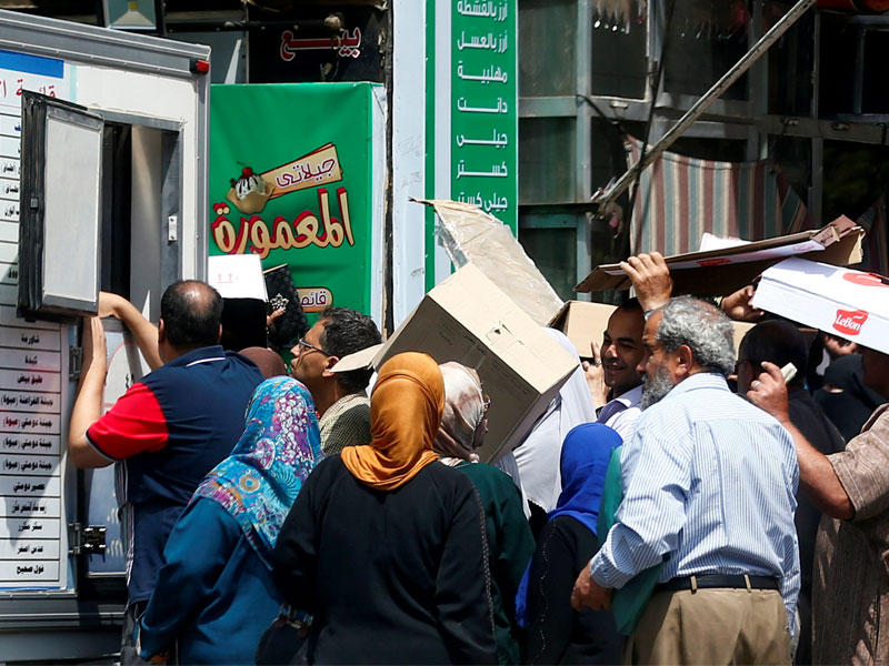 مصريون ينتظرون الحصول على مواد غذائية من منفذ بيع للجيش وسط القاهرة أمسt(رويترز)