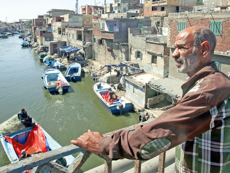 مصري يقف على جسر أعلى قناة فرعية للصيادين بمنطقة الماكس في الإسكندرية أمس (إي بي أيه)