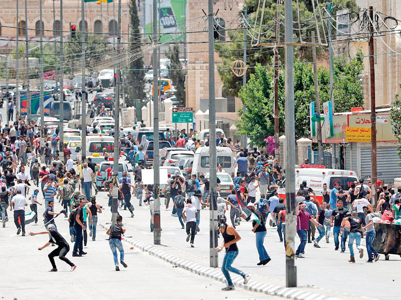 فلسطينيون يرشقون قوات إسرائيلية بالحجارة خلال مسيرة ببيت لحم في الضفة الغربية المحتلة أمس (أ ف ب)