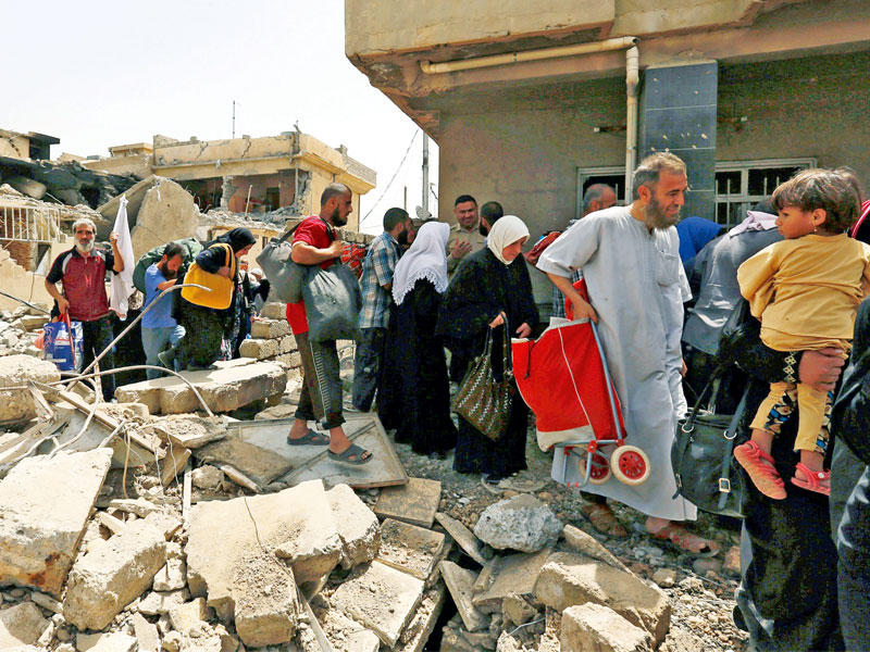 مدنيون عراقيون يفرون من أحد أحياء وسط الموصل أمس (رويترز)