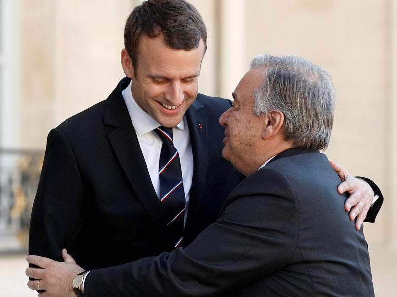 ماكرون مستقبلاً الأمين العام للأمم المتحدة أنطونيو غوتيريس على أدراج الإليزيه أمس الأول (رويترز)