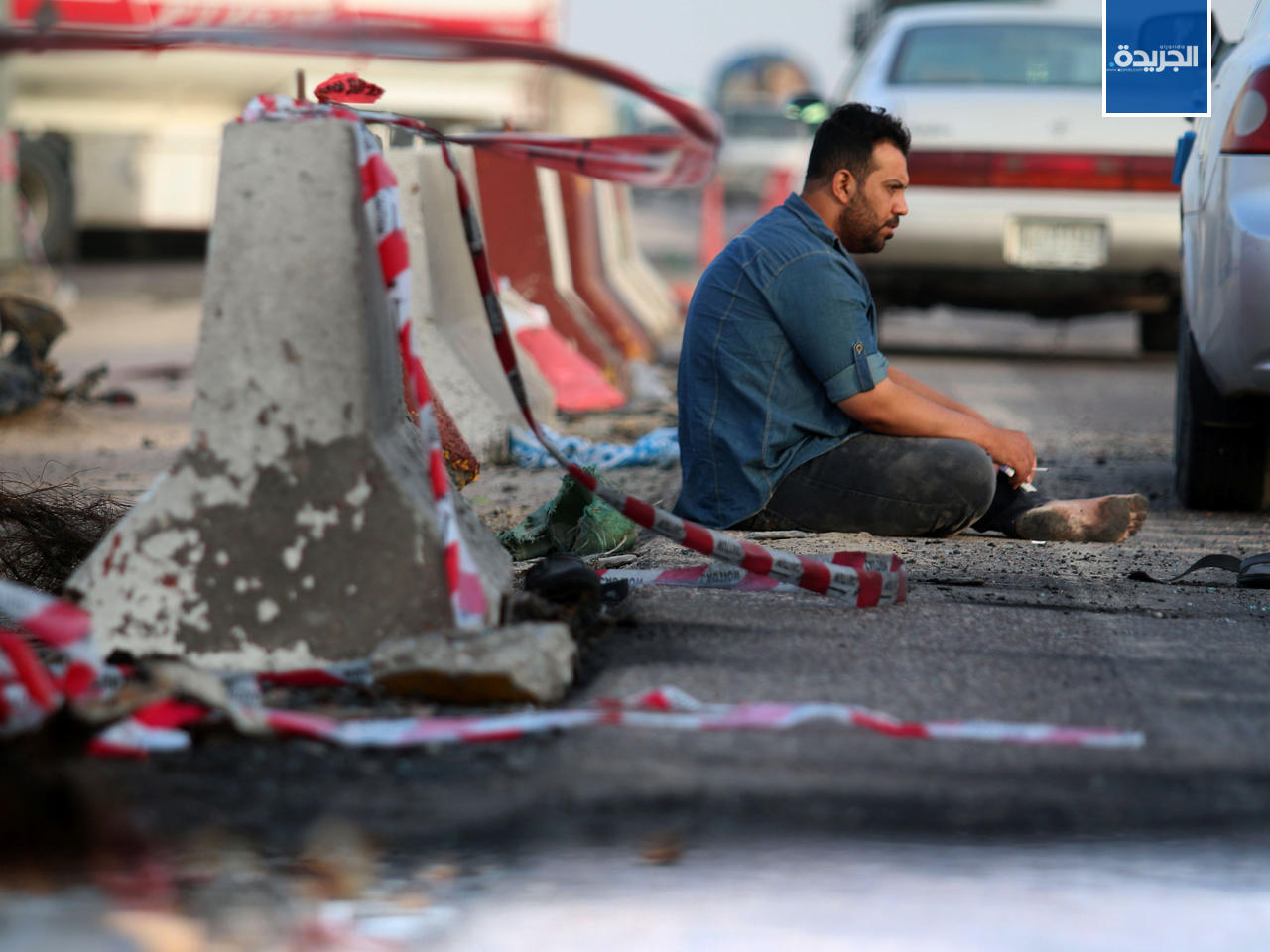 عراقي يجلس على الاسفلت في موقع تفجير سيارة مفخخة فى مدينة البصرة جنوبي العراق