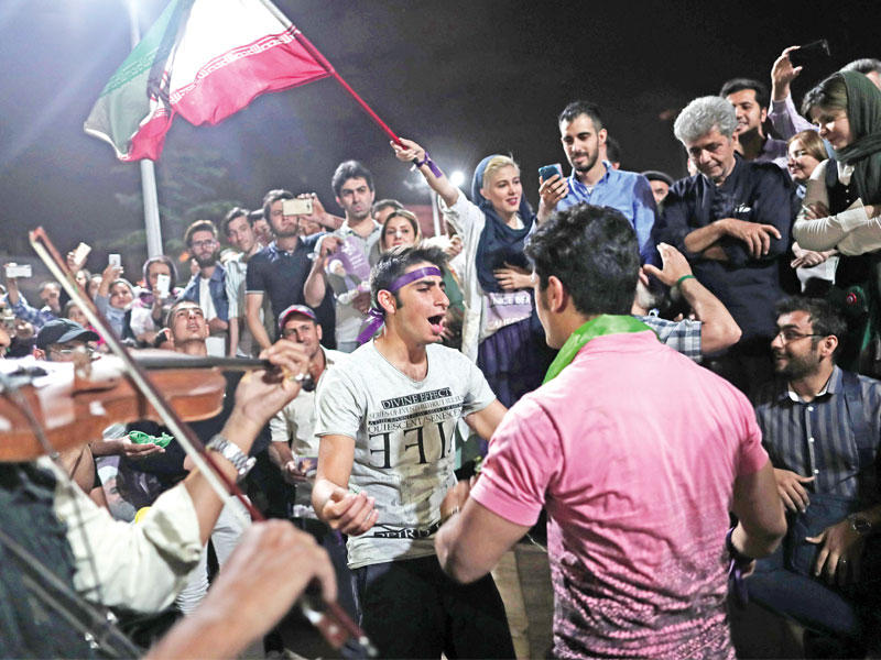 مشهد غير مألوف لإيرانيين يرقصون ويعزفون الموسيقى في أحد شوارع طهران مساء أمس  (أ ف ب)