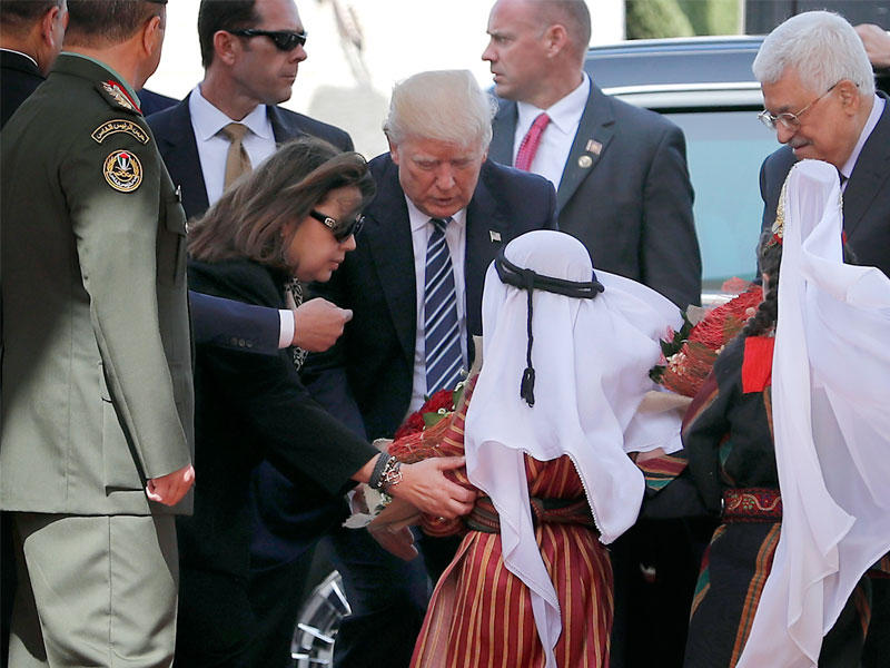 طفل فلسطيني يهدي لترامب باقة ورد لدى وصوله إلى القصر الرئاسي بمدينة لحم بالضفة الغربية اليوم (أ ف ب)