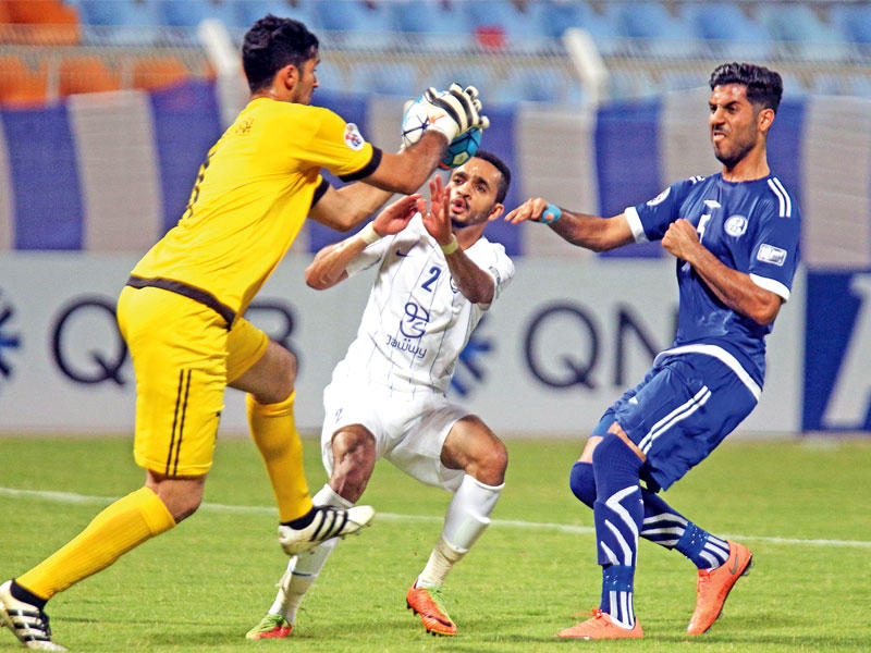 حارس مرمى الاستقلال يلتقط الكرة قبل ظهير أيمن الهلال محمد البريك (أ ف ب)