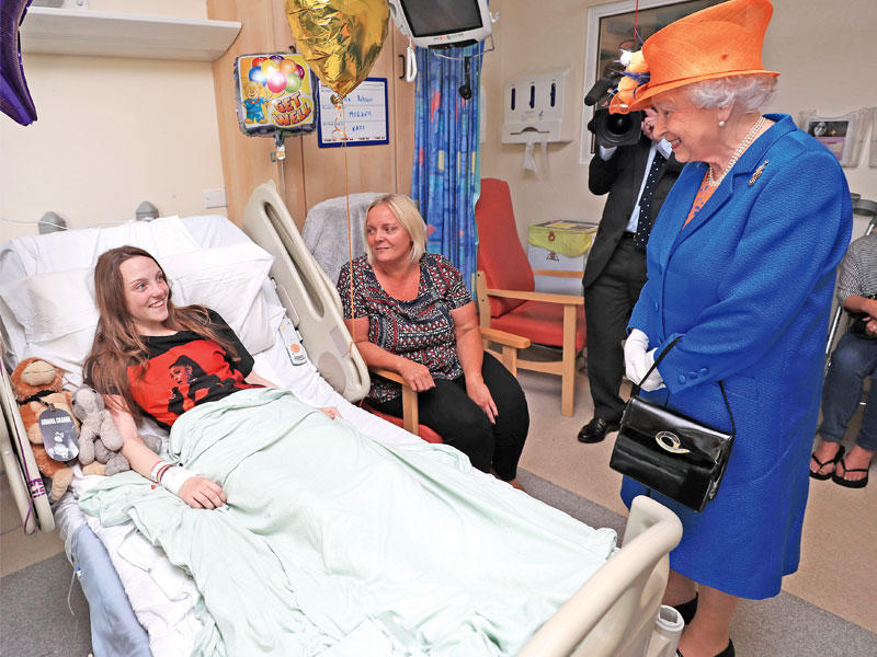 الملكة إليزابيث متحدثة للجريحة ميلي روبسون (15 عاما) في مستشفى مانشستر الملكي للأطفال أمس t(أ ف ب)