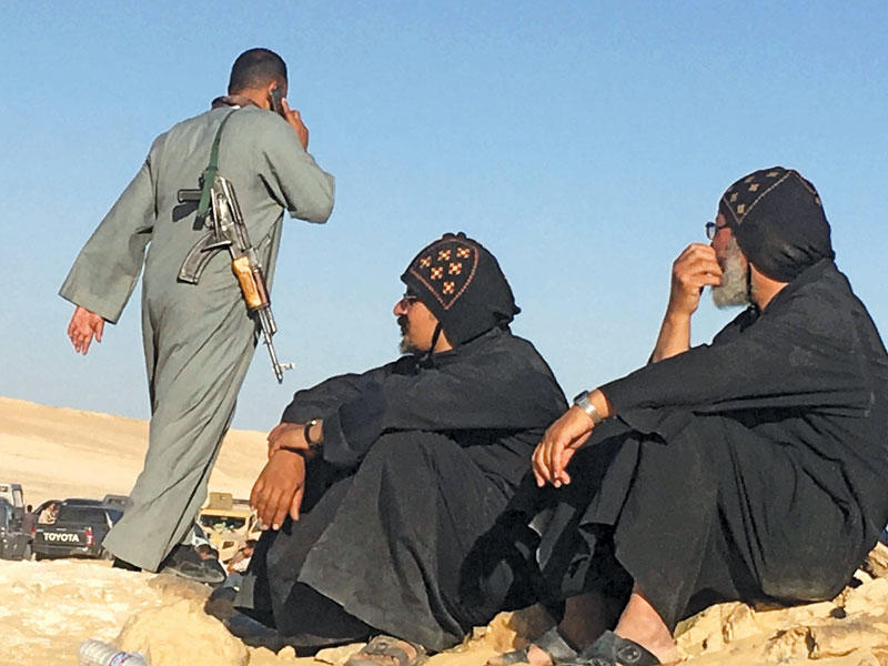 عنصر أمني يمر أمام رجلي دين مسيحيين قرب موقع الهجوم أمس