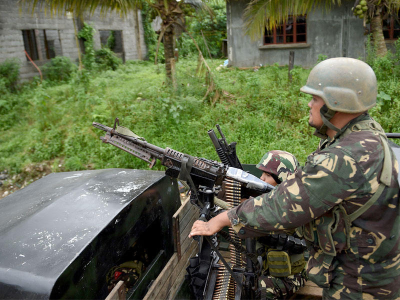 القوات الحكومية تقف على متن شاحنتهم وهم يرافقون عمال الانقاذ الذين انقذوا سكانها على مشارف ماراوي