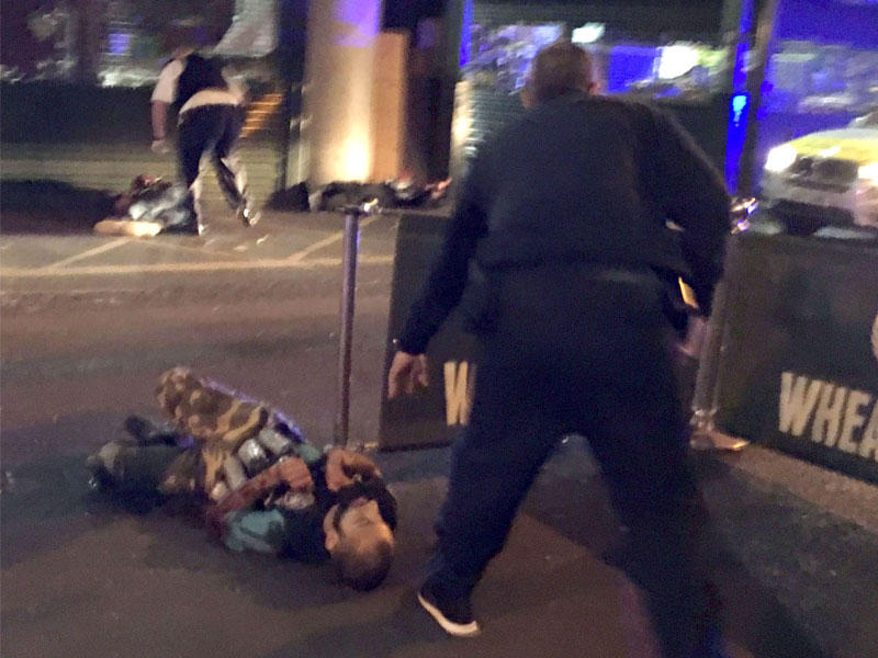 شرطي مسلح يقترب من جثة أحد المهاجمين خارج سوق بارا أمس ( أ ف ب)