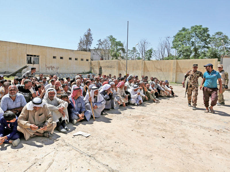 عدد من النازحين في نقطة تفتيش للتأكد من عدم انتمائهم لـ «داعش» غرب الموصل أمس (د ب أ)