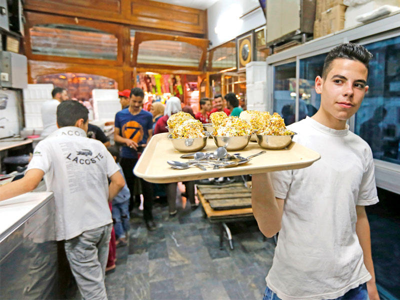 عمال في محل بوظة «بكداش» الشعبية في سوق الحميدية أمس ( أ ف ب)