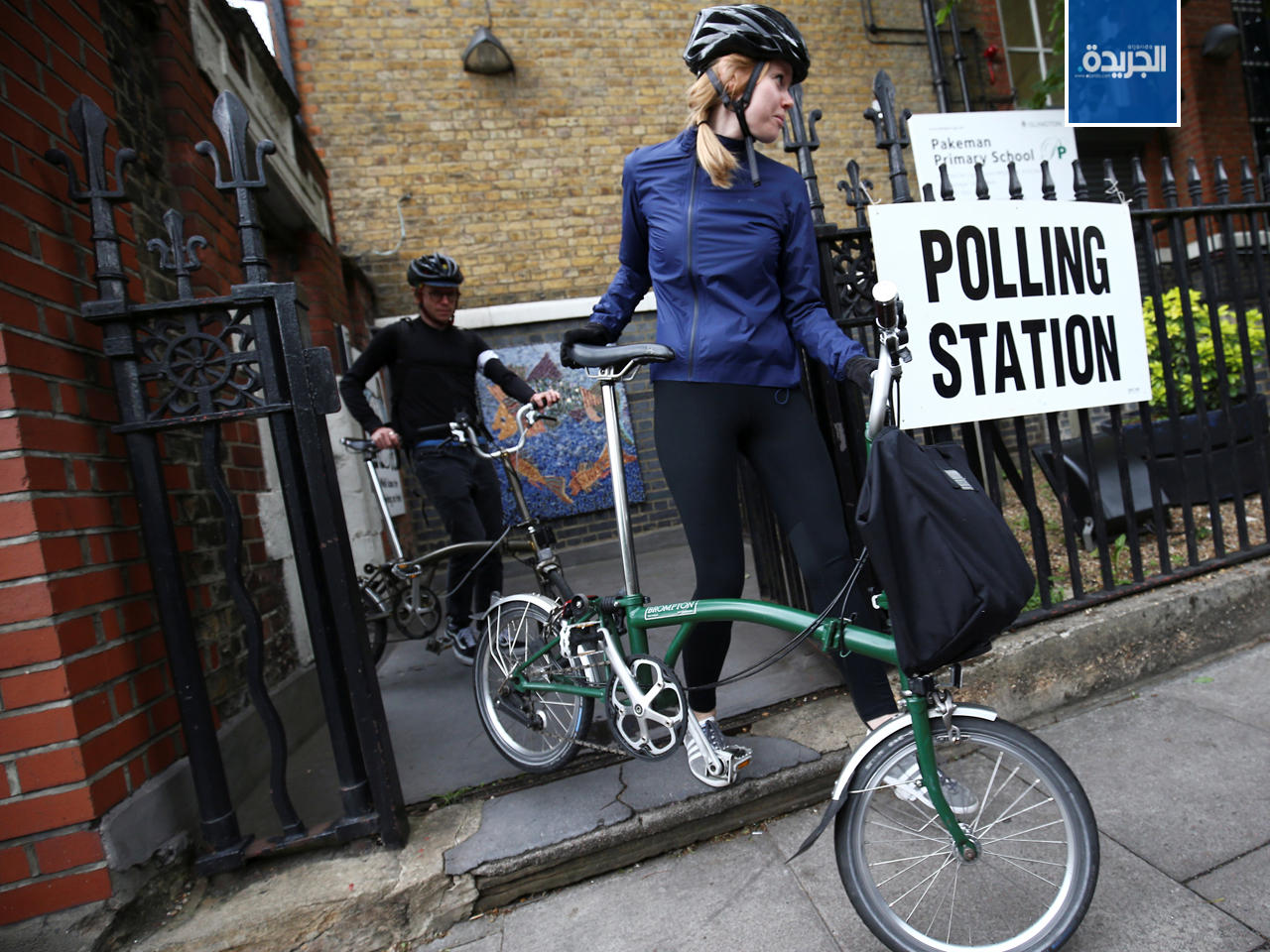 شخصان يحملان دراجاتهما أثناء مغادرتهما بعد التصويت في يوم الانتخابات العامة في لندن