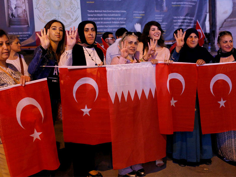 مؤيدات للدوحة يلوحن بالأعلام التركية والقطرية خلال تظاهرة في وسط إسطنبول أمس (رويترز)