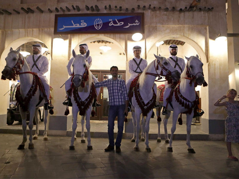 رواد سوق شعبي بالدوحة يلتقطون الصور مع خيالة الشرطة أمس (أ ف ب)