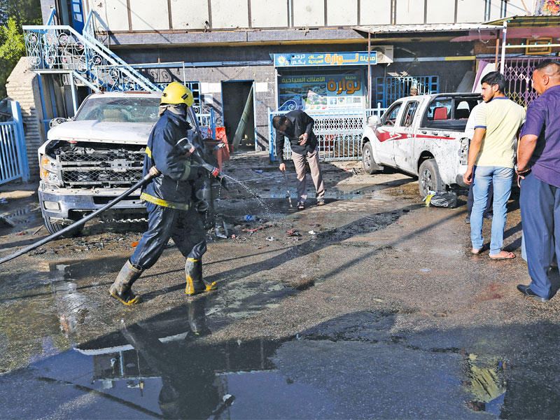 عناصر من الدفاع المدني ينظفون ركام التفجير في كربلاء أمس (رويترز)