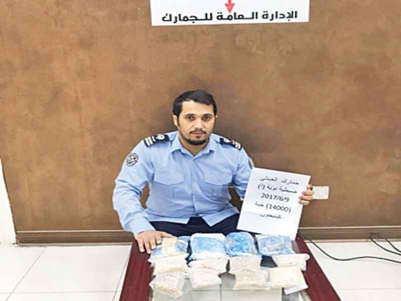 رجل جمارك يعرض الحبوب المخدرة المضبوطة