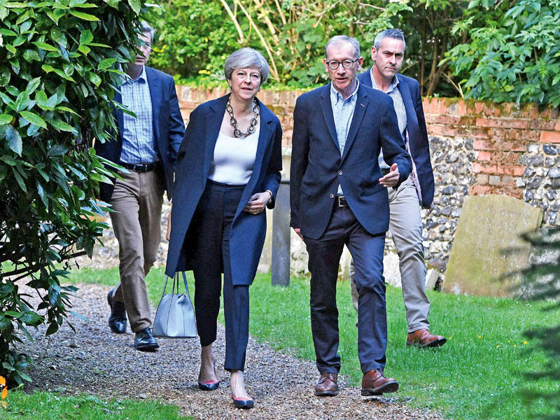 ماي وزوجها فيليب أثناء زيارتها لكنيسة سانت أندرو في دائرتها الانتخابية في ميدنهيد أمس ( اي بي ايه)