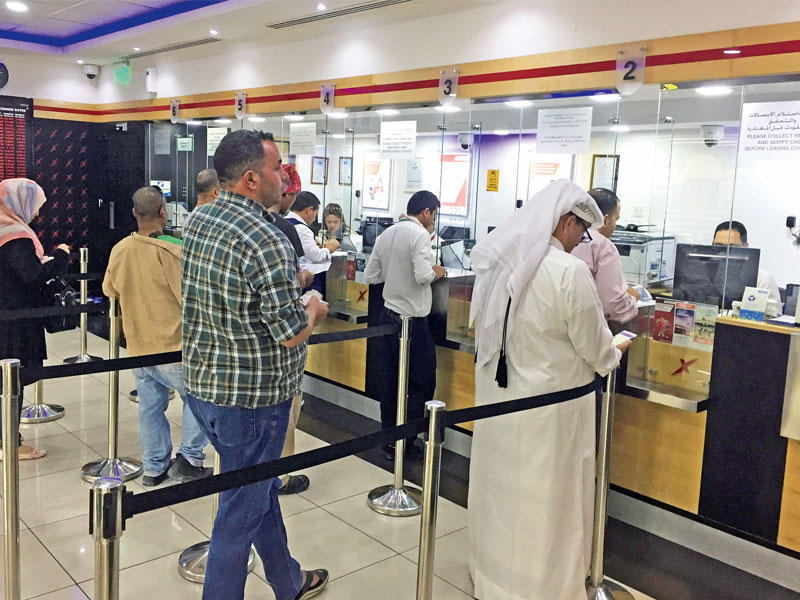 قطريون ومقيمون يستبدلون العملات  في مكتب صرافة بالدوحة أمس (رويترز)
