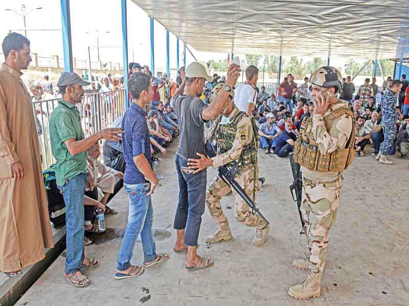 القوات العراقية تجري عملية تفتيش على النازحين قبيل دخولهم المناطق الآمنة في الموصل أمس الأول (أ ف ب)