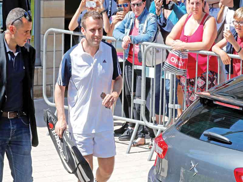 الرئيس ماكرون أثناء مغادرته منزله للعب التنس قبل يوم من الانتخابات في لوتيكه أمس (رويترز)