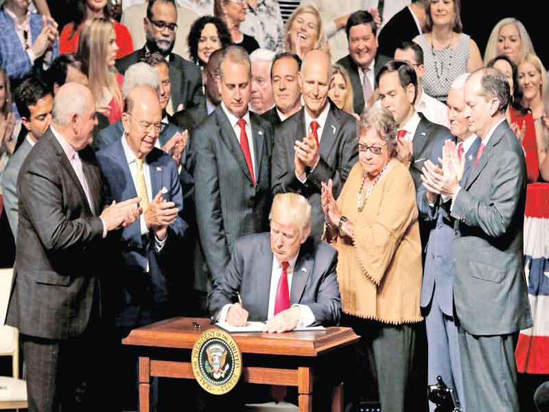 ترامب أثناء توقيعه على  وثيقة إلغاء الاتفاق الأحادي الجانب مع كوبا في حي ليتل هافنا بميامي فلوريدا أمس الأول (رويترز)