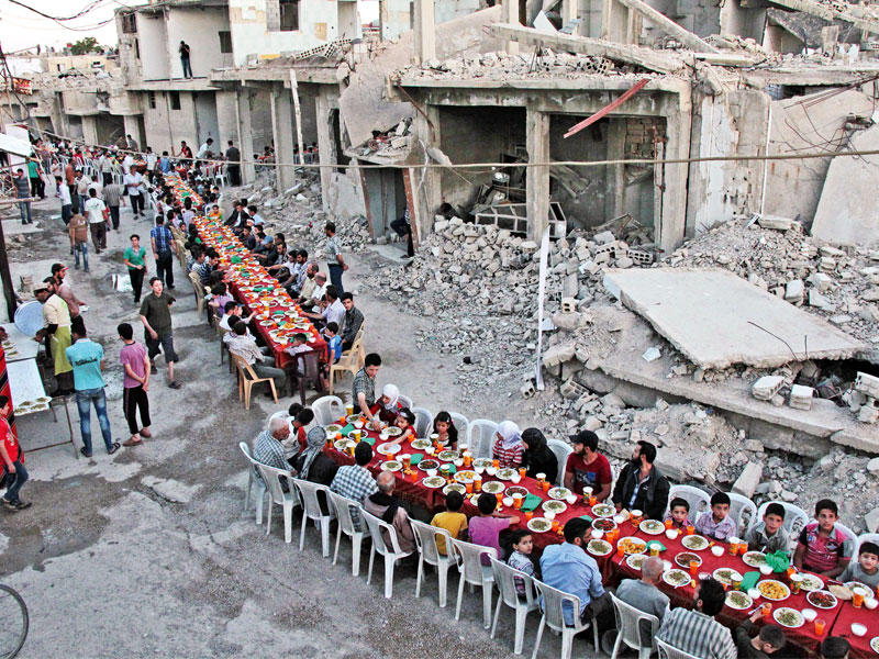 سوريون يتناولون الإفطار مساء أمس الأول، وسط المباني المدمرة في مدينة دوما الخاضعة للمعارضة قرب دمشق (أ ف ب)n