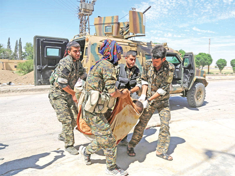 عناصر وحدات حماية الشعب الكردية ينقلون زميلاً لهم أصيب في الرقة إلى مشفى ميداني في قرية رقة سمرا الأربعاء   (أ ف ب)