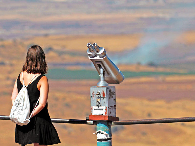 سائحة إسرائيلية تتابع عمليات القصف على الجانب السوري من مرتفعات الجولان أمس الأول (أ ف ب)