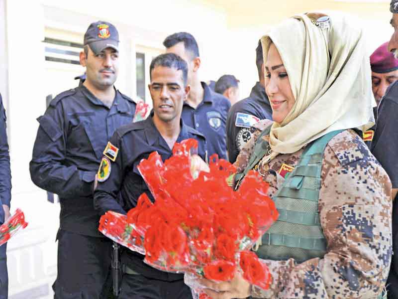 عضوة بخدمات مكافحة الإرهاب تقدم الزهور إلى كبار الضباط في عيد الفطر غرب الموصل أمس (رويترز)