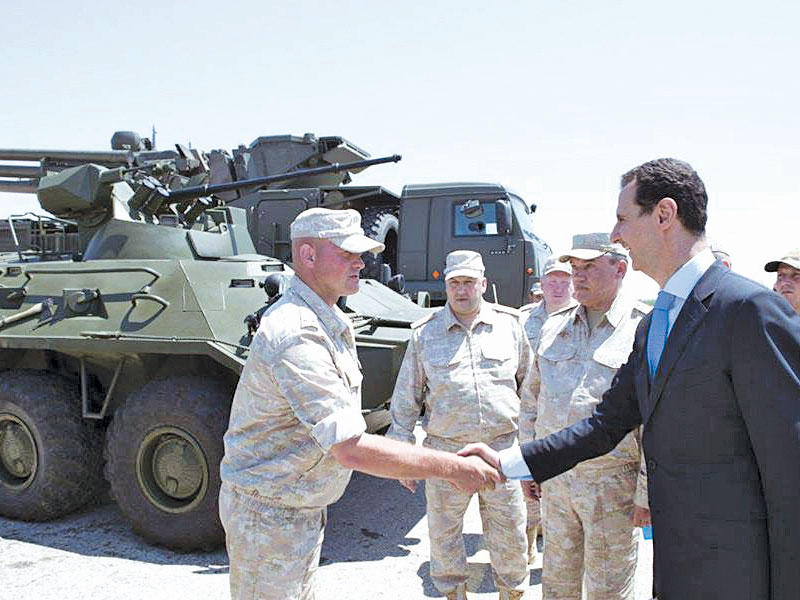 الأسد يصافح جنوداً روسيين في قاعدة حميميم باللاذقية أمس 