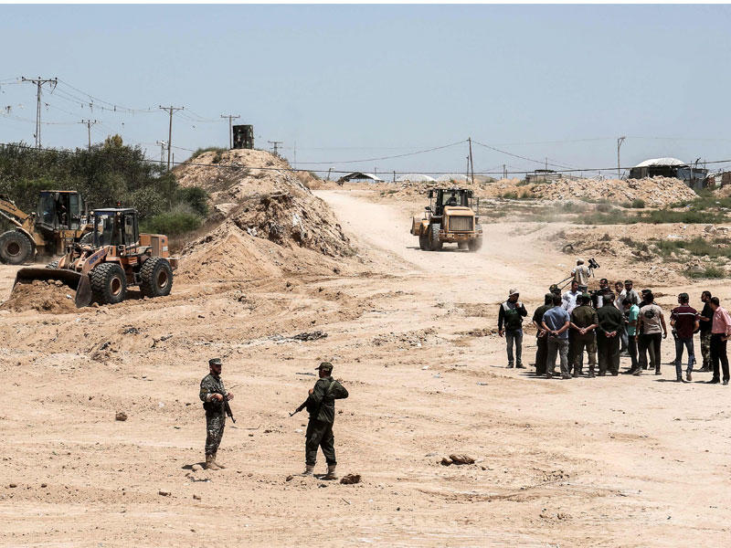 عناصر تابعة لـ«حماس» قرب آليات بدأت تنفيذ المنطقة العازلة على طول الشريط الحدودي الفاصل بين قطاع غزة وسيناء أمس (أ ف ب)