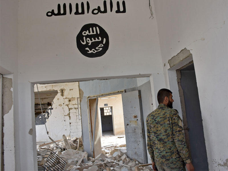مقاتلا من القوات الحكومية السورية يسير  في منزل داعش