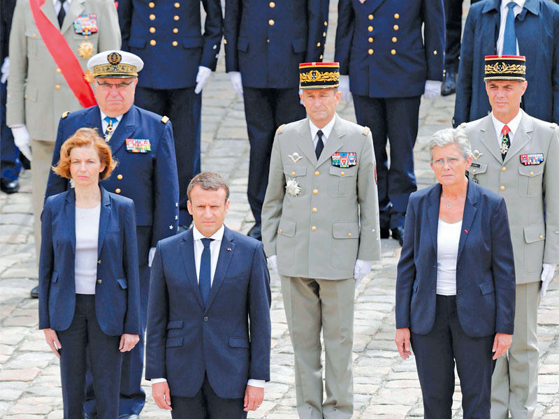 ماكرون وخلفه وزيرة الدفاع ومساعدتها وقادة الجيش خلال احتفال عسكري في لوباليه ديزينفاليد في باريس أمس (أ ف ب)n