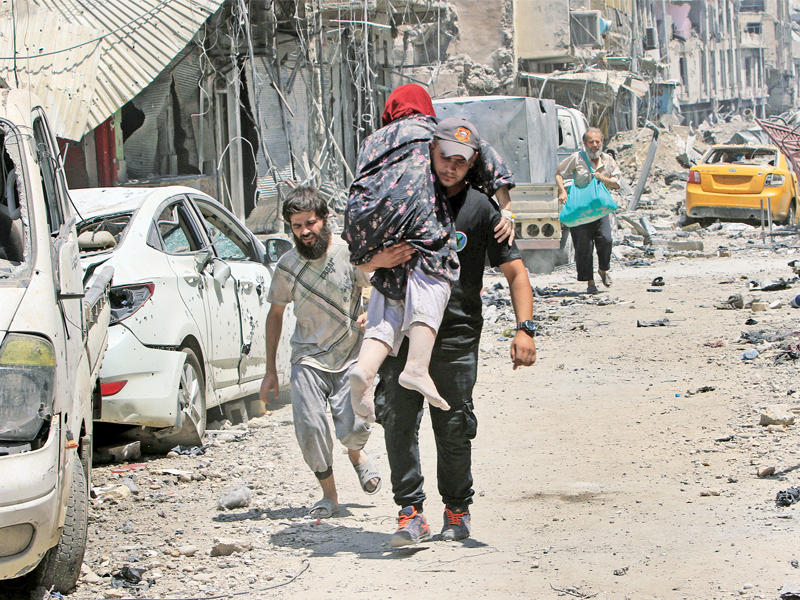 عراقيون يخرجون من الموصل المدمرة أمس (رويترز)