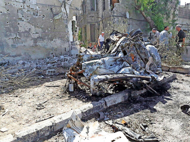 سوريون يتفقدون السيارة المنفجرة على طريق مطار دمشق اليوم     (إي بي إيه)