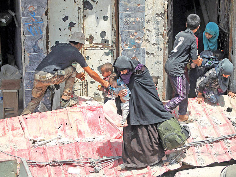 جندي عراقي يجلي أسرة من الوسط التاريخي للموصل أمس (أ ف ب)