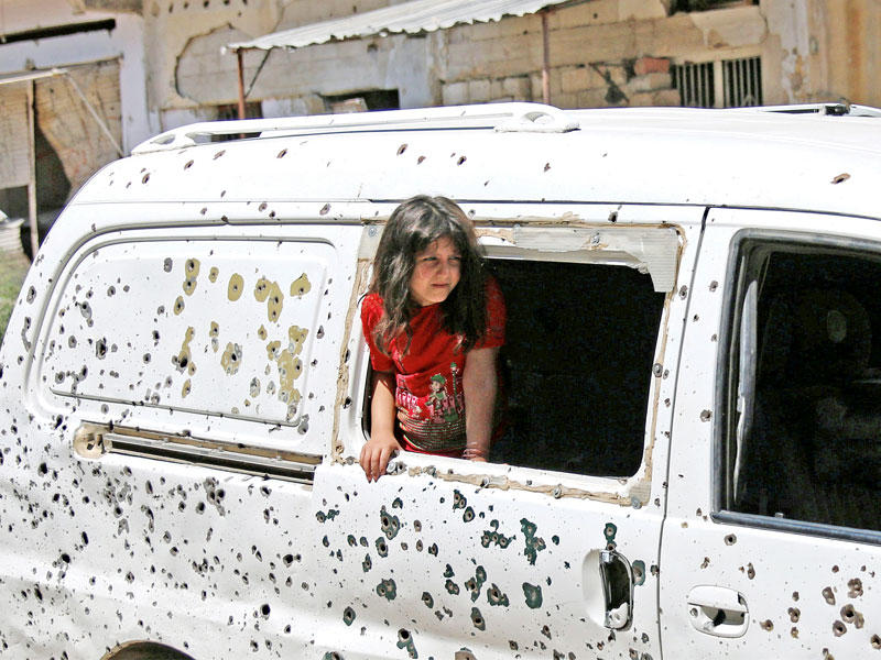 صبية سورية تطل من نافذة حافلة تبدو عليها آثار طلقات الرصاص في درعا  اليوم   (رويترز)
