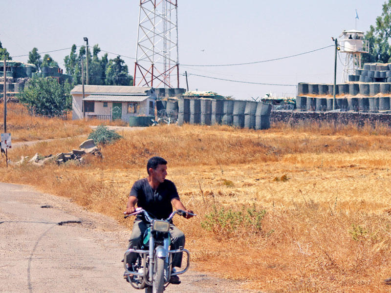 سوري يمر بدراجته النارية بالقرب من نقطة تفتيش تابعة لقوة الأمم المتحدة في القنيطرة أمس (رويترز)