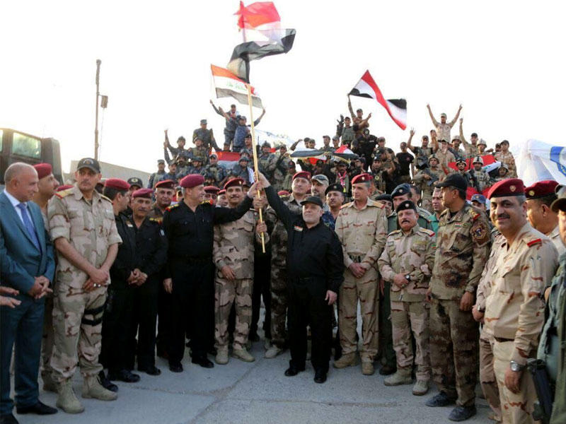 العبادي بين قادة الجيش العراقي يعلن استعادة الموصل بالكامل وتحريرها من «داعش» أمس (رويترز)