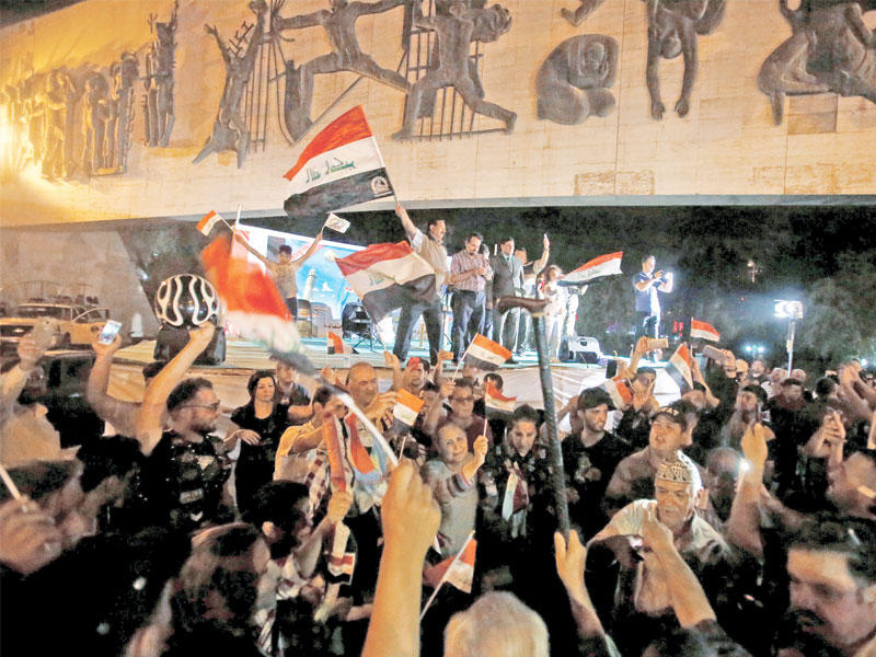 عراقيون يحتفلون بالنصر على «داعش» تحت نصب تمثال الحرية في ساحة التحرير وسط بغداد مساء أمس (رويترز)